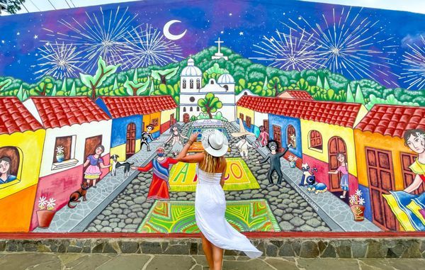 ruta de las flores tour, lady is posing in front a colorful mural located in Concepcion de Ataco, west El Salvador